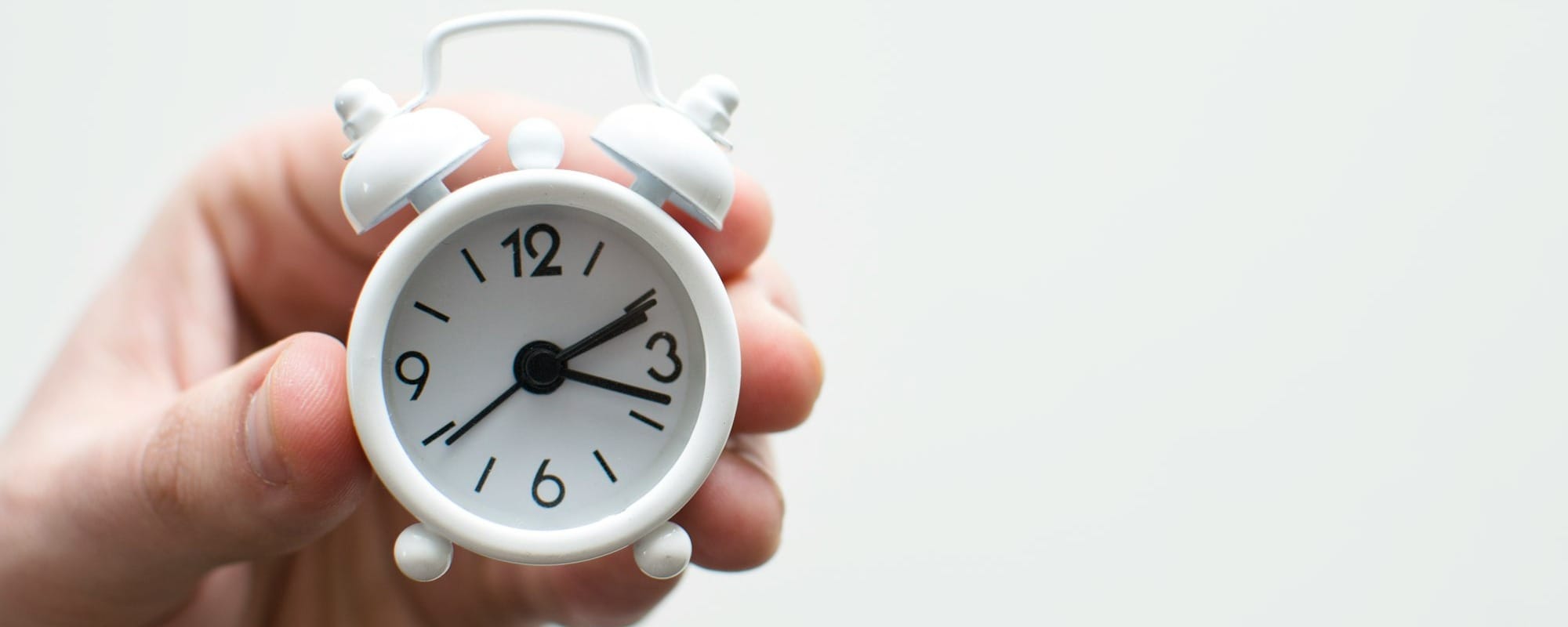 person holding white mini bell alarmclock